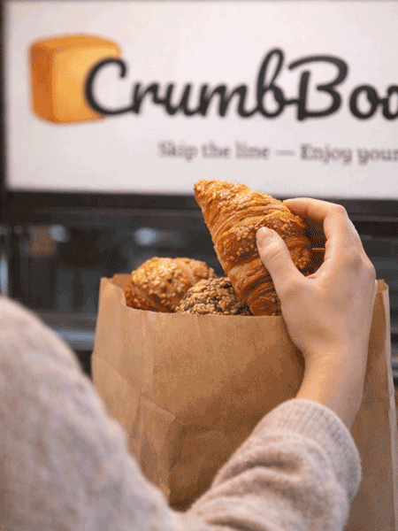 Frau holt Backwaren aus Papiertüte