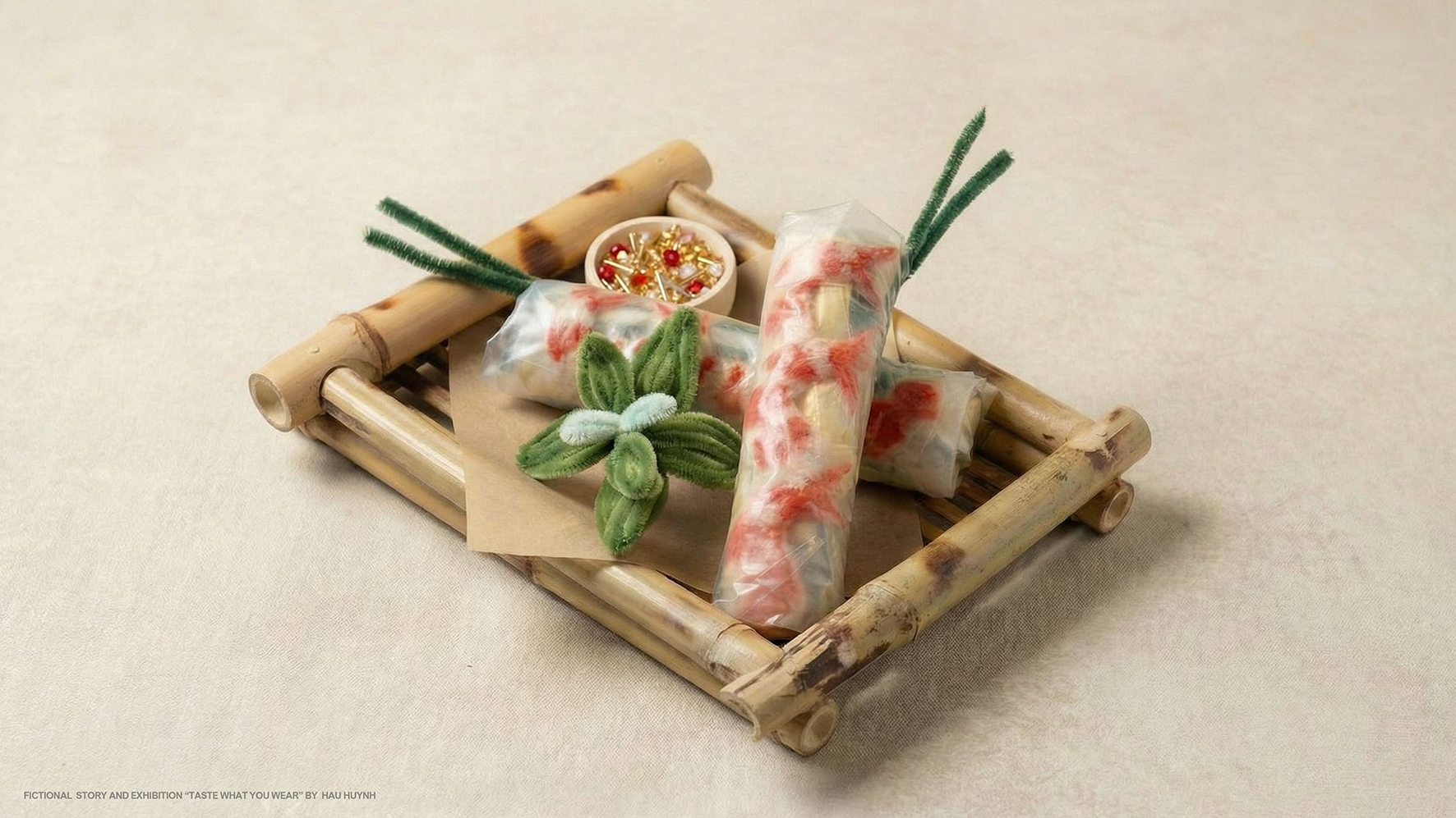 Stillleben: mehrere „Frühlingsrollen“ aus textilen Materialien auf einem Bambustablett, mit kleinen Dekoelementen.