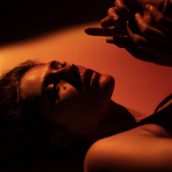 seitliches Portrait einer Frau in dramatischem orangefarbenen Licht mit extremem Schattenwurf