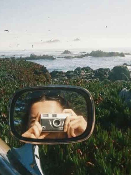 Frau mit Kamera – Spiegelung im Außenspiegel eines Autos